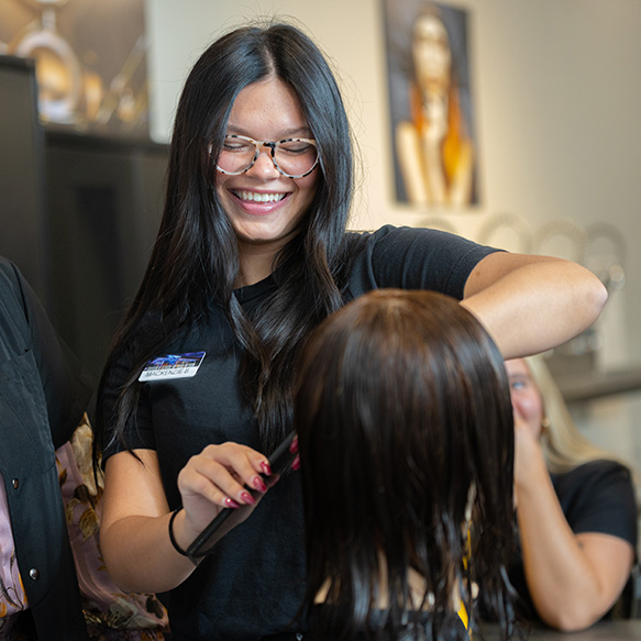 grabber student smiling while cutting hair.